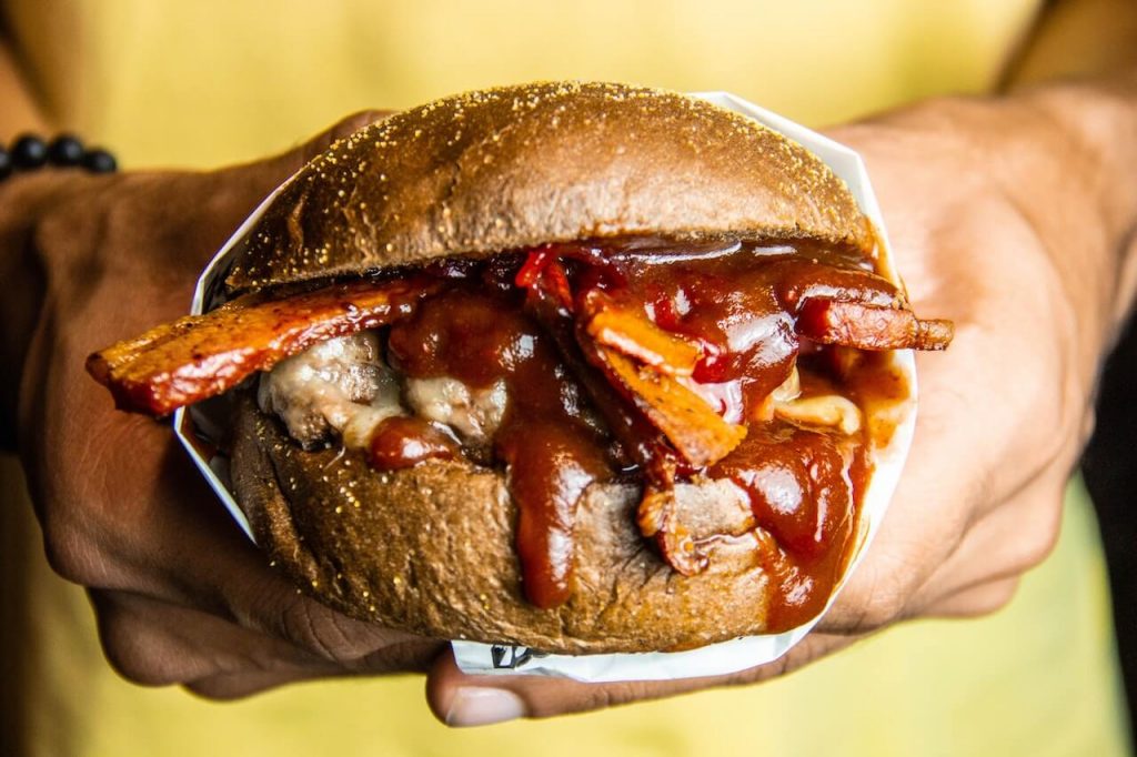 A mouthwatering burger, featuring rich, tangy barbecue sauce drips down the sides, adding a burst of flavor and hint of smokiness to the burger.