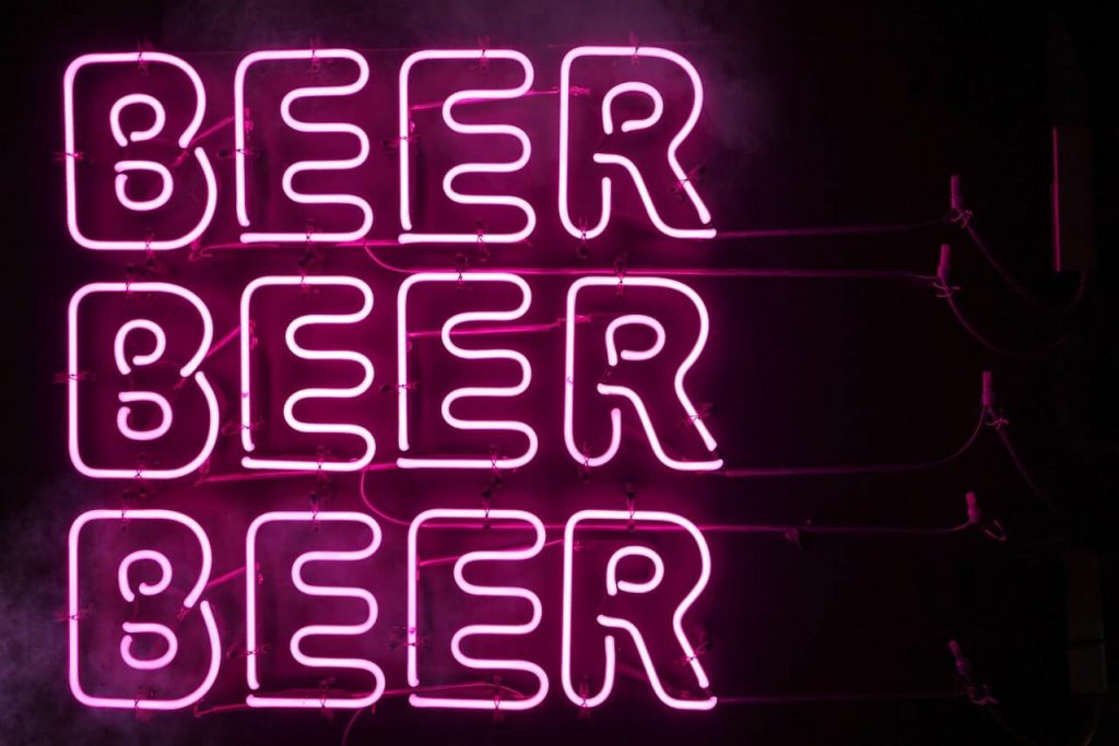 Three vibrant pink neon signs each sign features the word "beer" in capital letters, with curvy lines. 